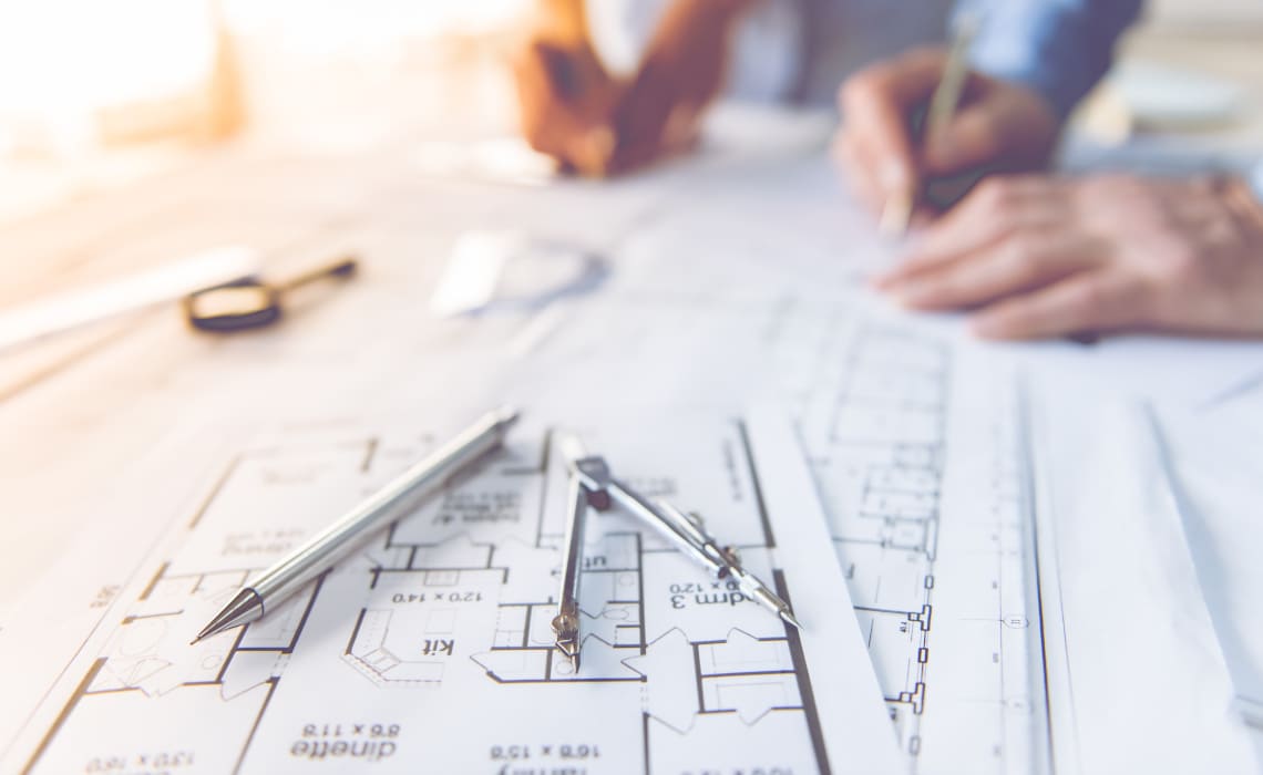 Architekt bei der Planung eines Bauprojekts anhand von Grundrisszeichnungen