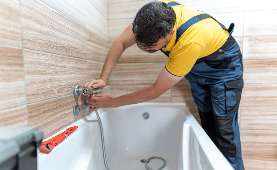 Installateur montiert Armaturen bei der Badsanierung an einer Badewanne