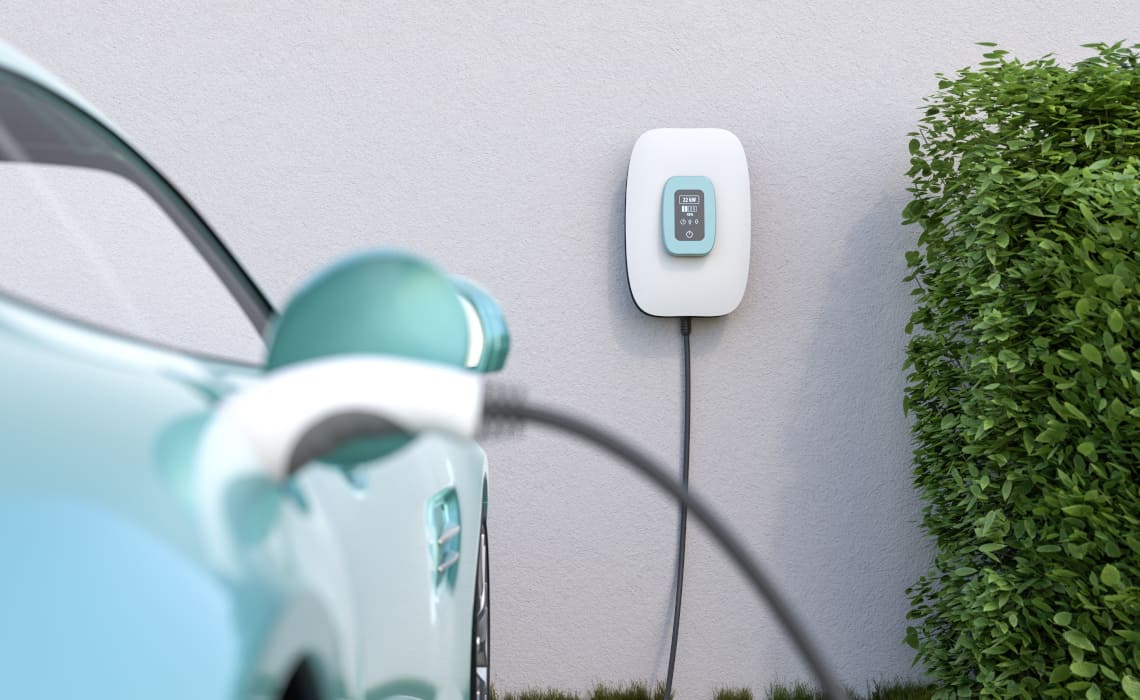 E-Auto wird an fest installierter Wallbox an der Hauswand geladen