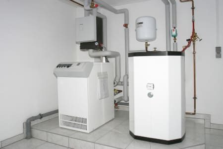 Alte Ölheizungsanlage mit Boiler und Rohrleitungen im Heizraum eines Wohnhauses