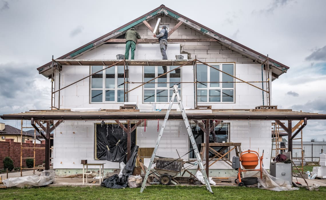 Fassade isolieren - Fassadendämmung an einem Einfamilienhaus – Handwerker isolieren die Aussenwand mit Wärmedämmplatten