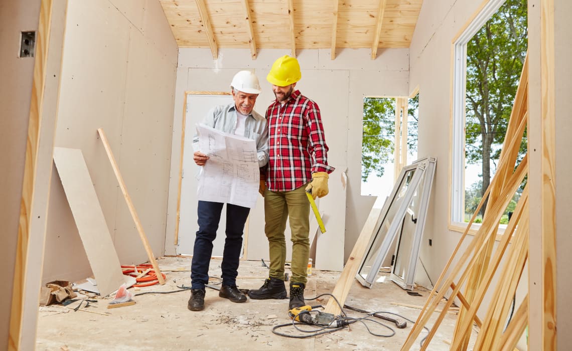 Haus renovieren - Handwerker planen eine Hausrenovation im Innenbereich anhand von Bauplänen