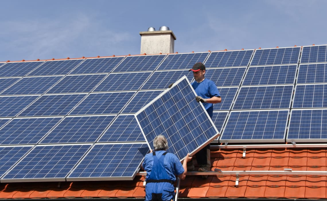 Monteure installieren eine Solaranlage auf dem Dach eines Wohnhauses