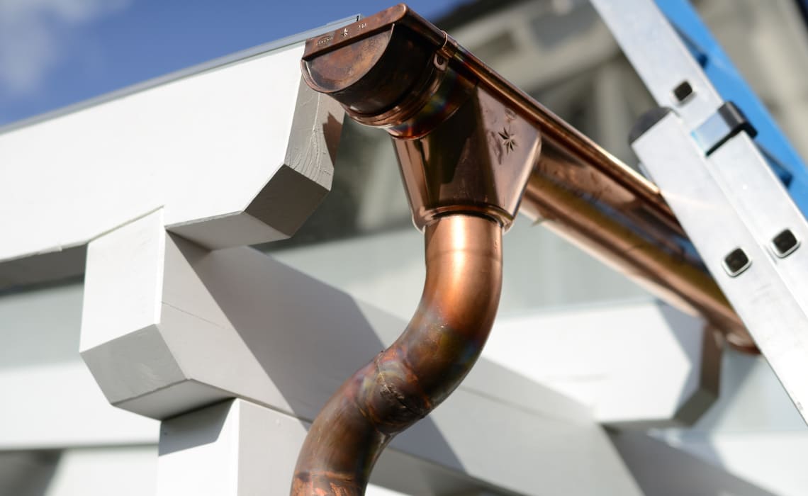 Spenglerarbeiten - Kupferne Dachrinne und Fallrohr bei professionellen Spenglerarbeiten am Hausdach